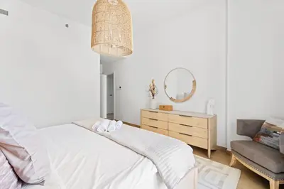 a bedroom with a bed and a chair and a mirror at Ocean View 2BR with a Pool & Gym, 2 min to Beach in Dubai