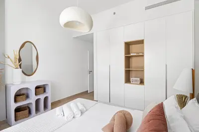 a white room with a bed and a mirror at Ocean View 2BR with a Pool & Gym, 2 min to Beach in Dubai