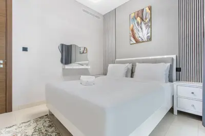 a white bedroom with a white bed and a tv at STAY BY LATINEM Luxury 1BR Holiday Home CVR A2003 near Burj Khalifa in Dubai