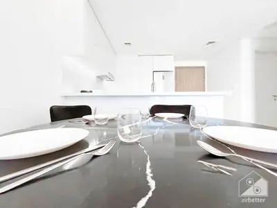 a dining table with white plates and wine glasses at Modern 1-Bedroom Haven in Ahad Residence in Dubai