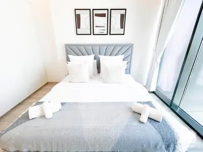 a bedroom with a bed with white sheets and pillows at Modern 1-Bedroom Haven in Ahad Residence in Dubai