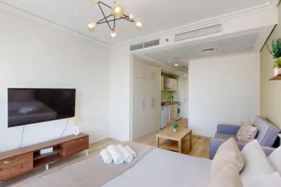 a bedroom with a large white bed and a couch at Goldcrest Views 2 - Elegant Studio in Dubai