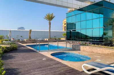 a swimming pool in front of a glass building at Goldcrest Views 2 - Elegant Studio in Dubai