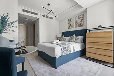 a bedroom with a blue and white bed and a table at Stonetree - GoldCrest Views 2 - Peaceful Community in Dubai