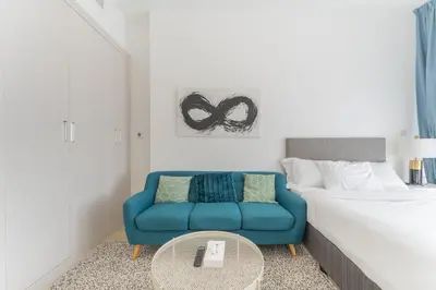 a bedroom with a blue couch and a bed at HAVN - Studio Apartment in Bloom Towers, JVC in Dubai