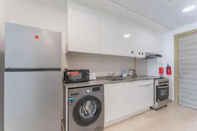 a kitchen with a washing machine and a refrigerator at HAVN - Studio Apartment in Bloom Towers, JVC in Dubai