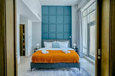 a bedroom with a large bed with an orange blanket at New Modern Apartment 1BHK 5 min walk to Dubai Mall 99walk score in Dubai