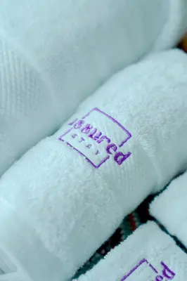 a close up of white towels with a purple stitching at Brand New 2BHK Luxury Apartment 7min to Dubai Mall 1.5 Bath in Dubai