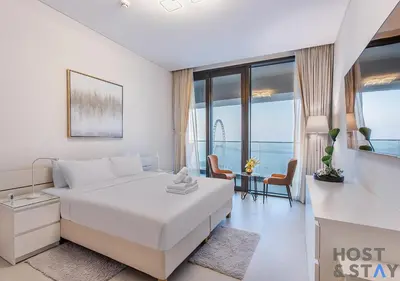 a white bedroom with a bed and a table and chairs at Highfloor 2-BR in Address Jumeirah Beach Residence in Dubai