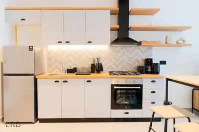 a kitchen with white cabinets and a refrigerator at New Cozy 1BR Dubai Hills in Dubai