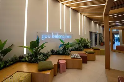 a lobby with benches and plants and a sign that says you belong here at New Cozy 1BR Dubai Hills in Dubai