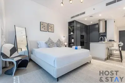 a white bedroom with a bed and a kitchen at Boutique Studio in Wilton Park MBR City in Dubai