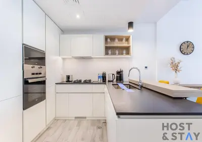 a kitchen with white cabinets and a counter top at 1BR Belgravia Apartment with pool view in Dubai