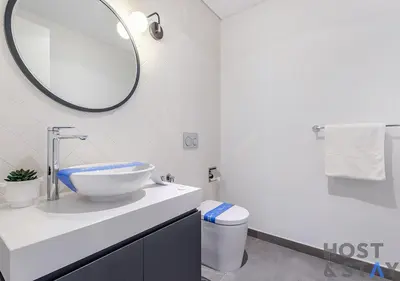 a white bathroom with a sink and a mirror at 1BR Belgravia Apartment with pool view in Dubai