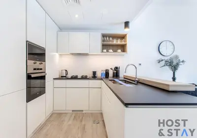 a kitchen with white cabinets and a clock on the wall at Comfy 1BR at JVC - Ideal for Family & friends in Dubai