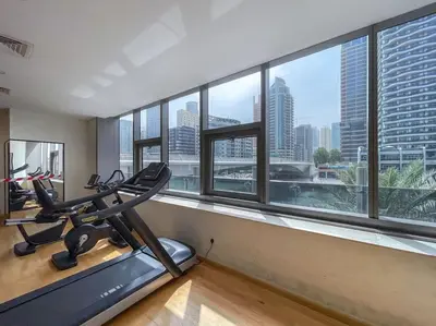 a gym with tread machines and a large window at Your gateway in Sparkle Tower JBR by Suiteable in Dubai