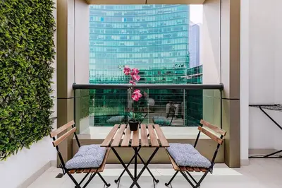 a table and chairs on a balcony with a window at DAMAC APARTMENTS in Dubai