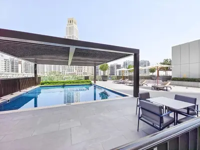 a patio with a table and chairs and a pool at The Harbor Heights 1BR in Palace Residences Creek in Dubai