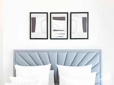 a set of three framed photographs above a bed with three pillows at Stylish 1Bedroom with Balcony & View Dubai in Dubai