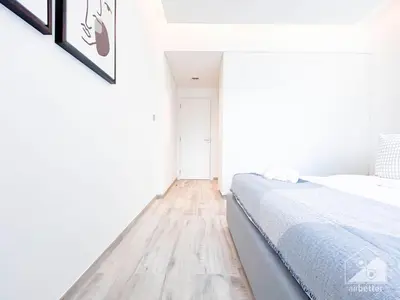 a white bedroom with a bed and a wooden floor at Stylish 1Bedroom with Balcony & View Dubai in Dubai