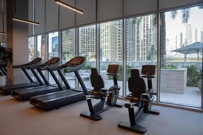 a gym with rows of tread machines and large windows at Elite Royal Apartment - Panoramic with Burj Khalifa & Full Fountain View - High Floor - Patron in Dubai