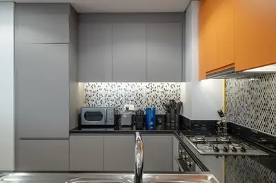 a kitchen with white cabinets and a sink and a microwave at 64th-Floor Rooftop Pool with Burj Khalifa View, 2BR Apartment in Paramount Hotel Midtown in Dubai