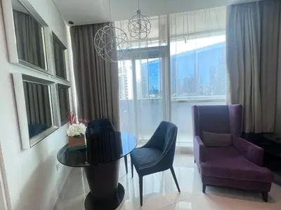 a living room with a table and chairs and a window at Damac Maison Distinction in Dubai