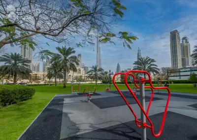 a red bike rack in a park with tall buildings at Damac Maison Distinction in Dubai