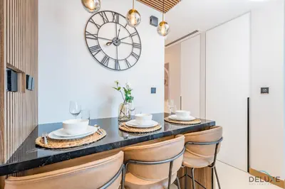 a dining room with a table and chairs with a clock on the wall at Chic 1BR in VIDA Residences Dubai Marina by Deluxe Holiday Homes in Dubai