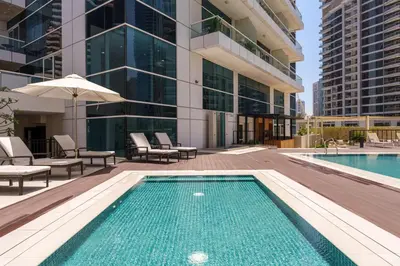 a pool with chairs and an umbrella next to a building at Marina Seaside Living prime location by the beach in Dubai