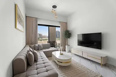 a living room with a couch and a tv at Charming 1Bedroom with pool and gym in Arjan in Dubai