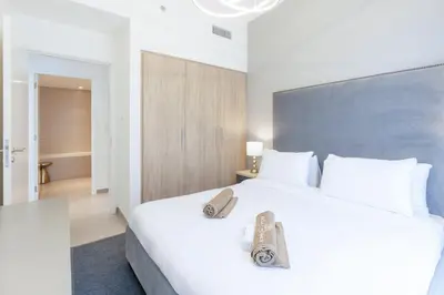 a bedroom with a large white bed with a book on it at Branded 2BR Residence with Direct Park Access in Dubai