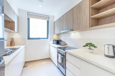 a kitchen with white counters and wooden cabinets at Branded 2BR Residence with Direct Park Access in Dubai