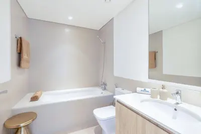a bathroom with a sink and a toilet and a mirror at Branded 2BR Residence with Direct Park Access in Dubai