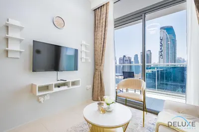 a living room with a tv and a large window at Charming 1BR Apartment in Vera Tower, Business Bay by Deluxe Holiday Homes in Dubai