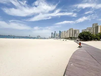 a sandy beach with a city in the background at Beachfront 1BR Retreat at Address JBR in Dubai