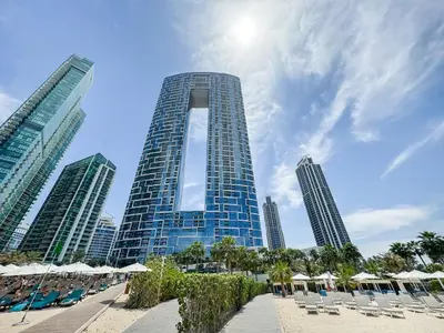 a tall building with chairs and umbrellas on a beach at Beachfront 1BR Retreat at Address JBR in Dubai