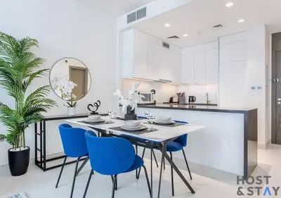 a kitchen with a dining table and blue chairs at 1 Bedroom - Crystal Lagoon - MBR City Meydan in Dubai