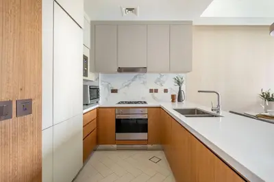 a kitchen with white counters and wooden cabinets at GuestReady - Downtown Dubai luxurious stay in Dubai