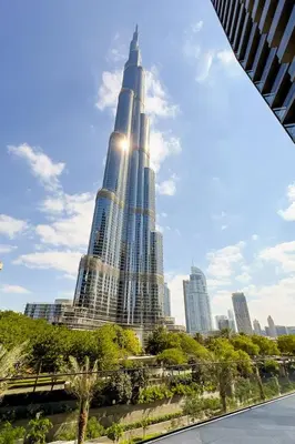 a tall building with the sun shining on it at GuestReady - Downtown Dubai luxurious stay in Dubai