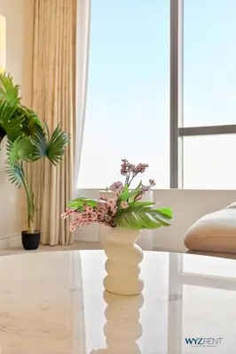 a vase with flowers on a table in a living room at Breathtaking 1BR in Palm Tower, with Sea View in Dubai