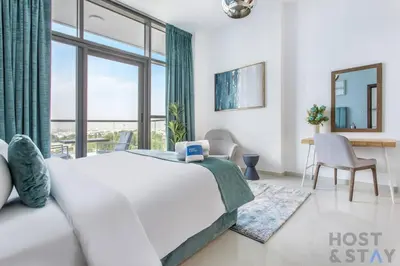 a bedroom with a bed and a large window at Serene 1 BR in Damac Hills - Host & Stay in Dubai