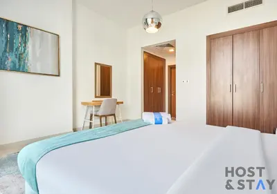 a bedroom with a bed and a wooden cabinet at Serene 1 BR in Damac Hills - Host & Stay in Dubai