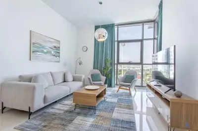 a living room with a couch and a tv at Lively 1 BR in Damac Hills, Dubai - Host & Stay in Dubai