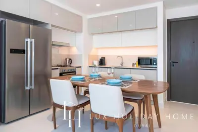 a kitchen with a wooden table with chairs and a refrigerator at LUX The Marina Vista Beachfront Suite 2 in Dubai