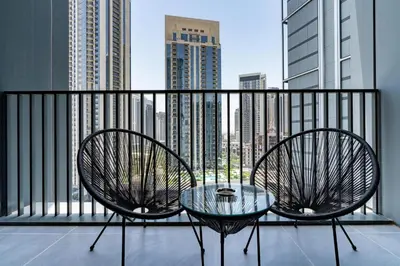 a balcony with two chairs and a glass table at GLOBALSTAY Creek Edge Tower Elegant Apartments in Dubai