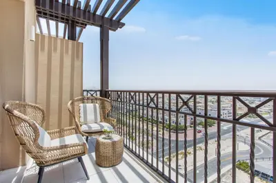 a balcony with wicker chairs and a view of a city at One Bedroom Apartment in Madinat Jumeirah Living by The S Holiday Homes in Dubai