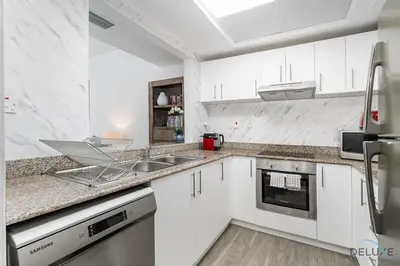 a white kitchen with white cabinets and a sink at Charming 1BR in The Point Tower, Dubai Marina by Deluxe Holiday Homes in Dubai
