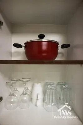 a red pot on a shelf with glasses on it at The Urban Oasis - Harmony in Dubai