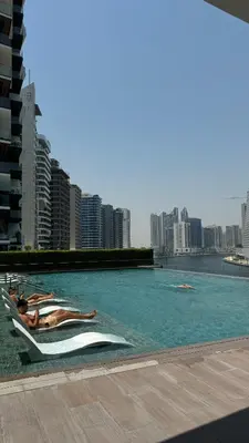two people laying in a swimming pool in a city at Exclusive Canal Waterfront Views 15 Northside in Dubai